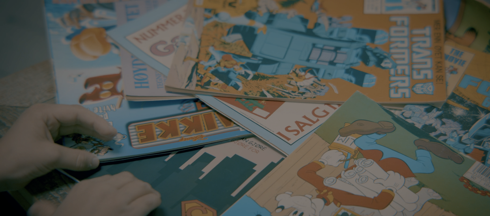 En hånd velger kundereisehelt bladet blant en mengde magasiner